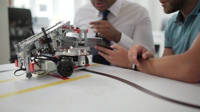 Close up shot of men discussing robotic devise in studio