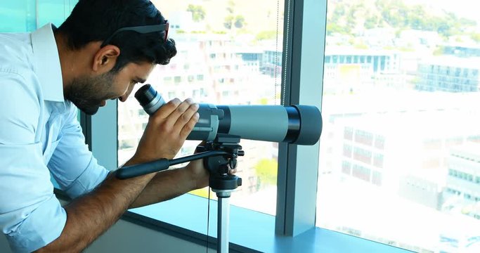 Male executive looking through telescope