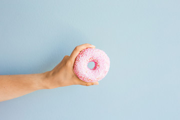 Woman holding pink delicious donut on blue background