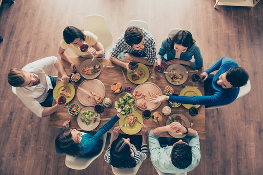 Friendship and communication concept. Top view of group of eight happy friends having nice food and drinks, enjoying the party and communication