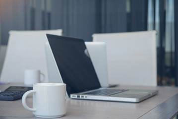Coffee cup of cappuccino with labtop computer on table in office