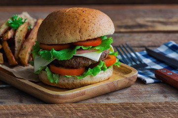 Homemade hamburger on plaid napkin with french fries. Delicious sandwich hamburger with meat or pork ham cheese and fresh vegetable. Hamburger or sandwich is the popular fast food for brunch or lunch.