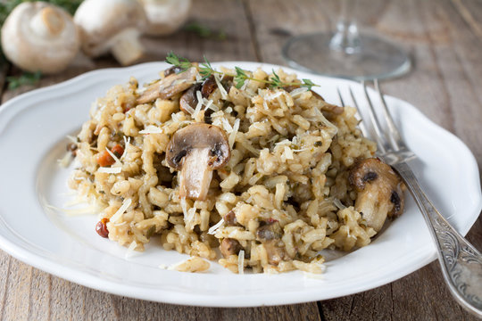 Mushroom risotto on white plate on wooden table. Closeup view