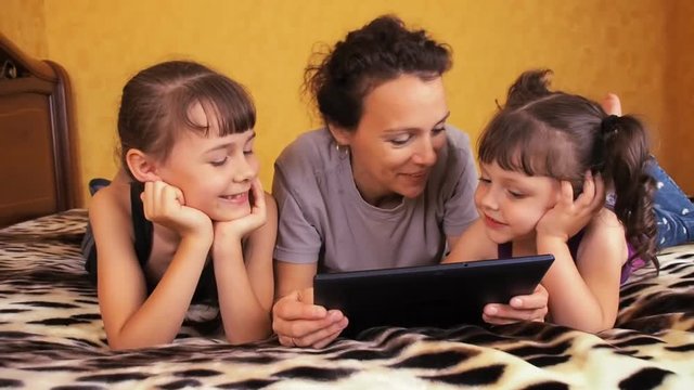 Mom and children laugh at the tablet. Family with a tablet.