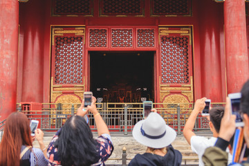 Group of tourists taking pictures of a monument in The Forbidden City in Beijing, China