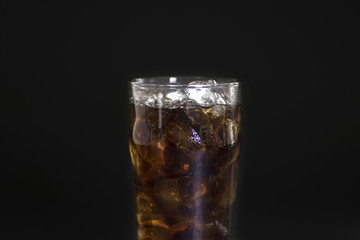 Coca Cola in a glass of ice on a black background.