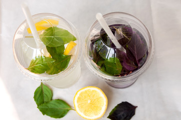 Two drinks: water with lemon and basil leaves