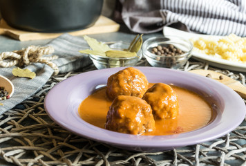 Meat balls of beef in tomato sauce served on a purple plate. As an addition to pasta