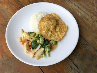 Vegetable stir fry with Omelette  in a white plate on wooden background. Thai style food. Vegetarian Food