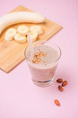 Fresh made banana smoothie in a glass on pink background