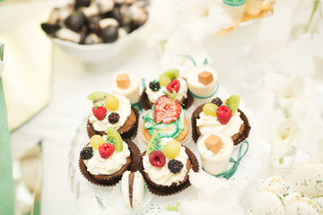 Delicious and tasty dessert table with cupcakes shots at reception closeup