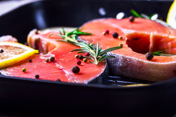 Salmon steaks in a grill pan with lemon, herbs and spices