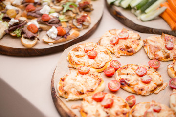 a lot of mini pizza, on wood plate. catering buffet. selective focus