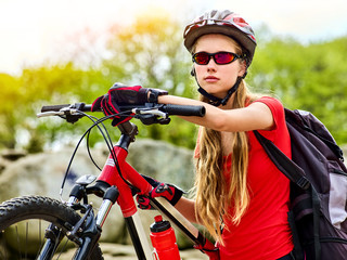 Woman on bicycle ride mountain. Girl with smart watch traveling in summer park. Cycling person with rucksack counts pulse after sport training. Sport trip is good for health and figure. School trip.