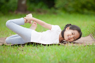 Cute asian little child girl doing exercise in the summer park