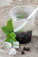 On the table, a drink with black currant and leaves