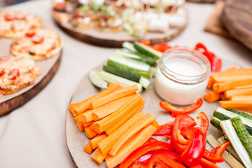 Fresh cucumber, carrot, red sweet paprika sliced in stripes on an olive wood cutting board