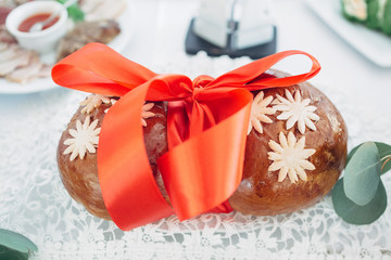 The bread with red bow stands on the wedding table