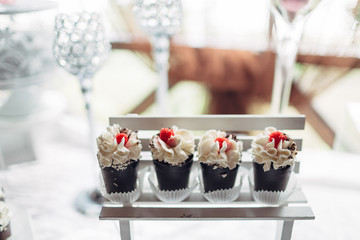 The cakes with raspberries stand on the buffet table