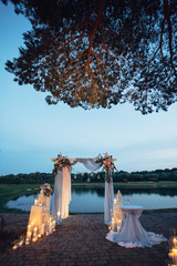 The archway with flowers and candles   for wedding ceremony stand near lake