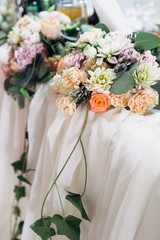 Green branches hang from the bouquets on the table