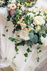 Green branches hang from the bouquets on the table