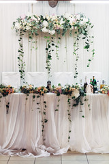 Green branches hang from the bouquets on the table