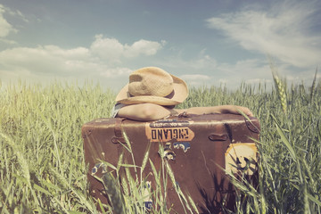 Young cowboy sleeps leaning against his suitcase in the middle of the prairie