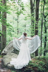 Bride stands alone in the summer forest