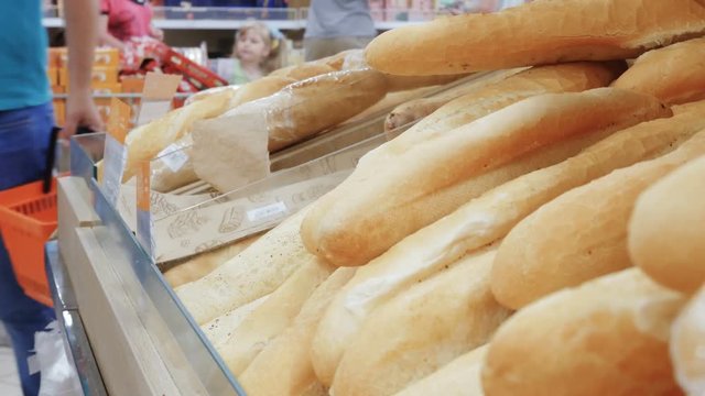 Woman buying fresh bread in a bakery products supermarket