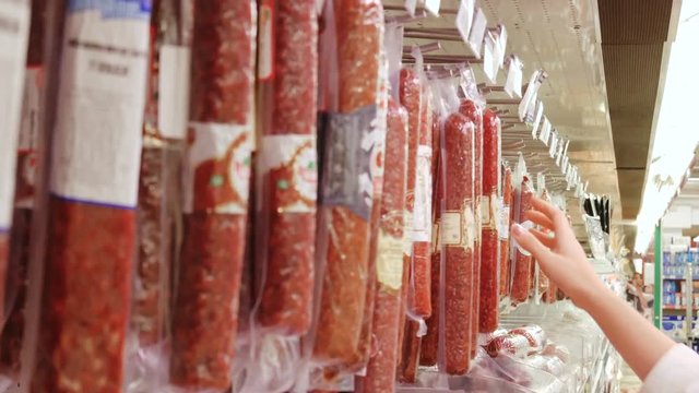 woman buys choosing a sausage in supermarket store
