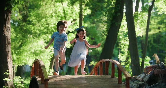 two children,a boy and a girl running in the Park, laughing happily ,slow motion