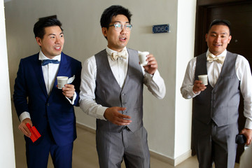 Groom and friends stand in the hall with paper cups in their hands