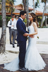 Naklejka premium Bride and groom hold each other hands posing outside on the wind