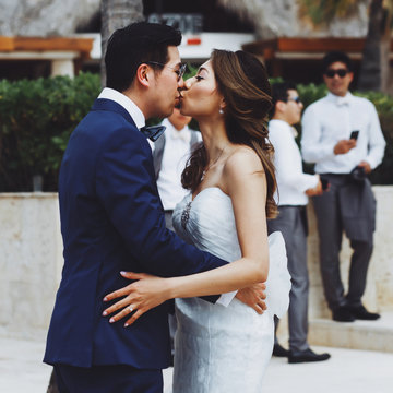 Tender kiss of wedding couple standing outside