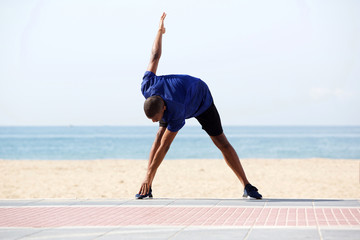 African man doing morning exercise on beach