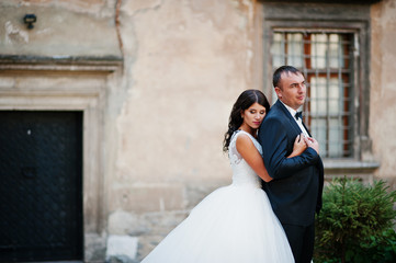 Amazing young attractive newly married couple walking and posing in the downtown with beautiful and ancient architecture on the background on their wedding day.