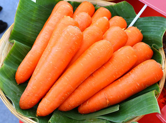 Fresh carrots in basket against banana leaf.