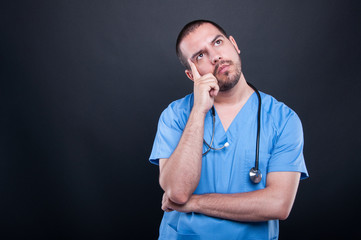 Portrait of doctor wearing scrubs with stethoscope thinking