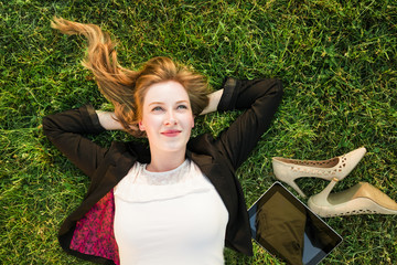 young independent woman relaxing on grass in park