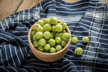 Fresh gooseberry in a wooden bowl.