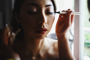 Obraz premium Woman holds eyeliner before bride's eye