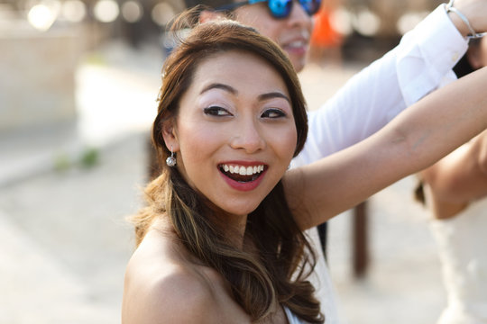 Cheerful Asian bride raises her hand up