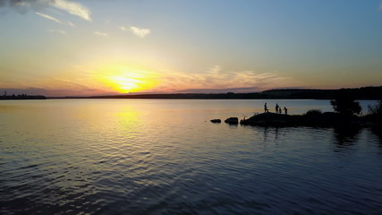 Fototapeta na wymiar People Enjoying the Riverside Sunset