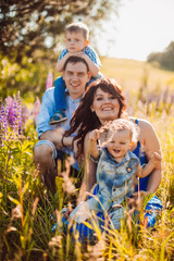 Obraz premium Happy family poses on the field in a sunny weather