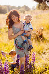 Lovely mother holds little son on her arms posing on the field