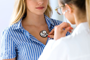Female doctor checking patient heartbeat using stethoscope. © nenetus