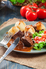 Pork meat stew served with potatoes and vegetable salad
