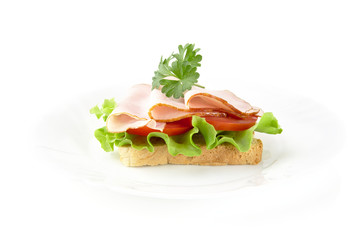 Slice of bread on plate with lettuce,cold cuts on white