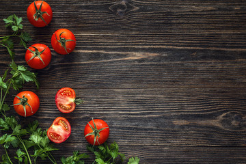 Fresh tomatoes and parsley on a dark wooden table with copy space.
